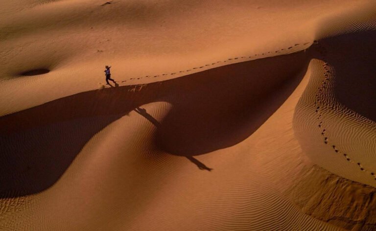 Camel trekking into the Sahara Desert dunes at sunset near Merzouga, Morocco