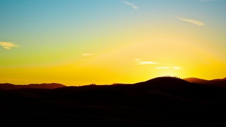 Golden sunset over the Sahara Desert dunes in Merzouga, Morocco, with breathtaking colors and peaceful desert landscapes