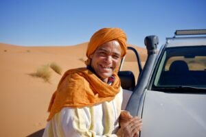 A local Moroccan driver beside his vehicle in the desert