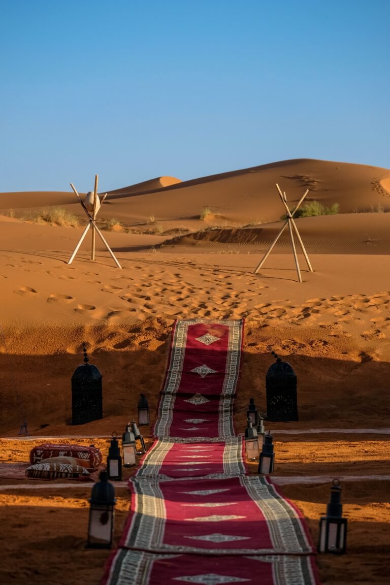 Moroccan carpet path with lanterns leading to a desert camp at sunset