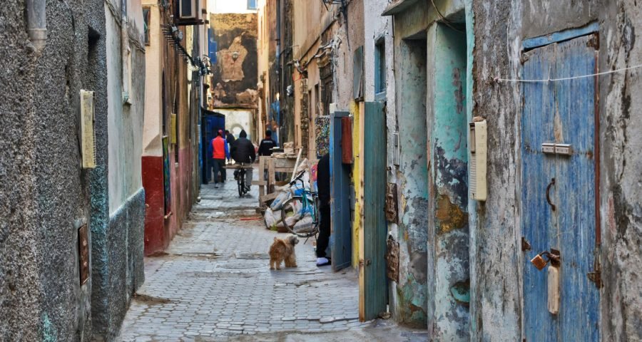 A narrow medina alley with unmarked doors, typical of where riads are tucked away