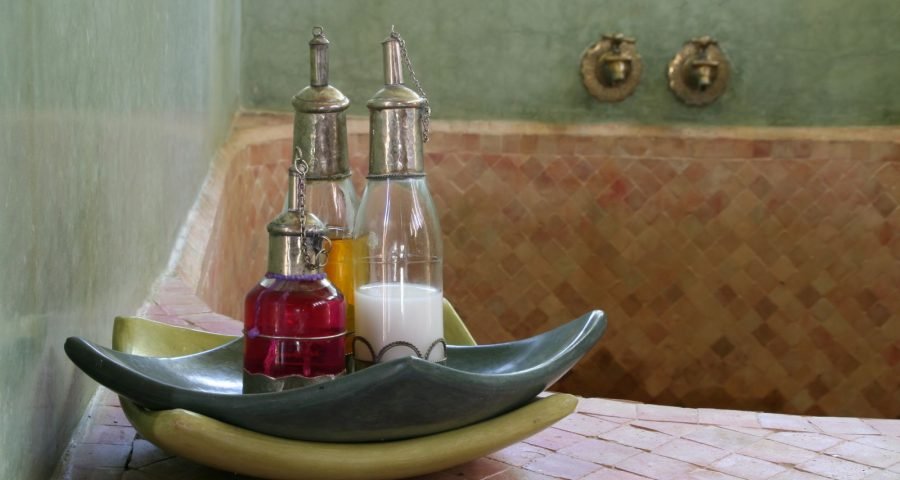 Traditional oils and soaps in a Moroccan hammam, set against zellige tilework