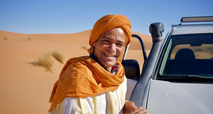 A local Moroccan driver beside his vehicle in the desert