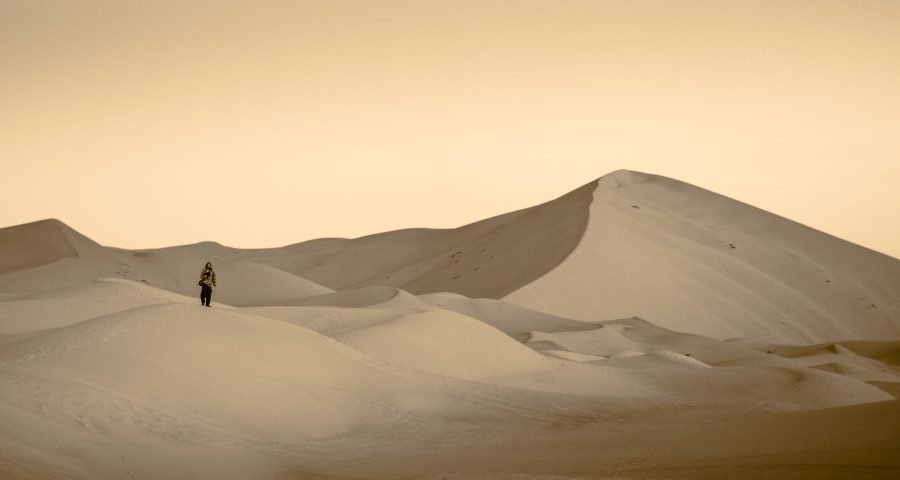 Solo traveler hiking alone across the Erg Chebbi dunes in Merzouga, Morocco